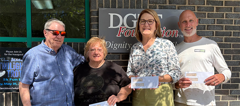 People standing in front of building holding checks